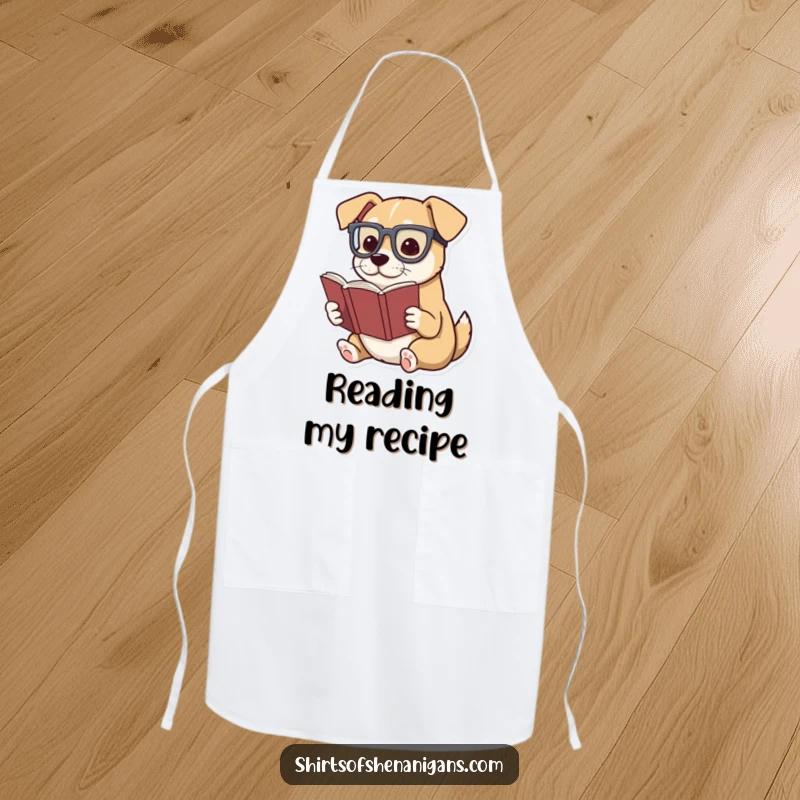Funny apron featuring a dog wearing glasses, dramatically reading a miniature book, literary kitchen theme.