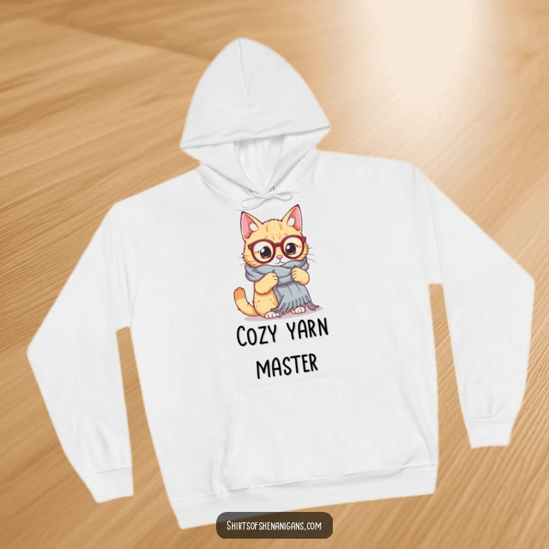 Funny Cat Knitting Hoodie: A cat in large glasses tries to knit a huge scarf, offering cozy comfort and humorous charm.
