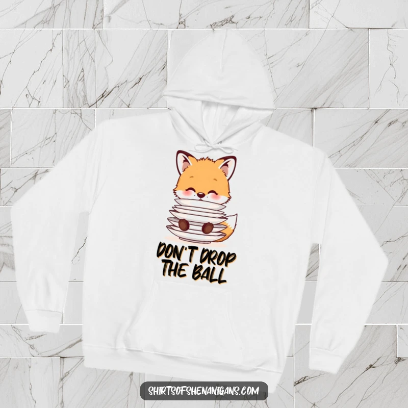Funny Hoodie: A cute fox cub balancing a stack of plates on its nose, offering warmth and a whimsical design for animal fans.