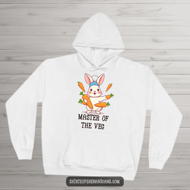 Funny hoodie with a rabbit in a chef hat comically juggling large carrots, exuding passion for cooking with a playful vibe.