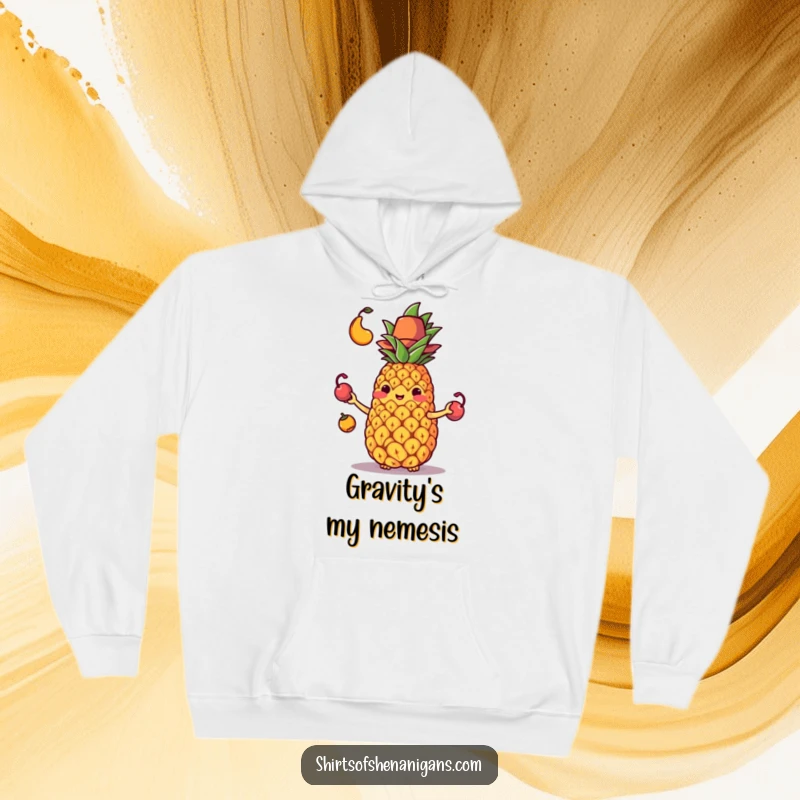 Funny hoodie depicting a flustered juggling pineapple in a tiny hat losing control of its fruit, a comical scene.