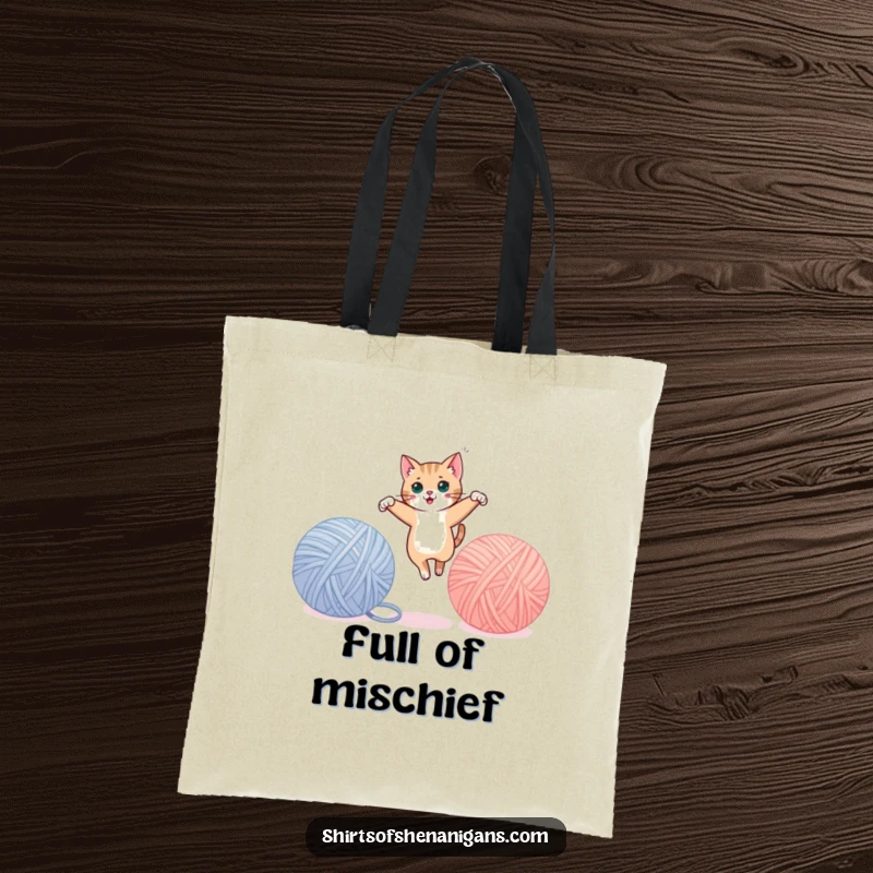 Funny cat tote bag showing a sleek cat leaping between giant yarn balls, ready for errands. A practical funny gift.