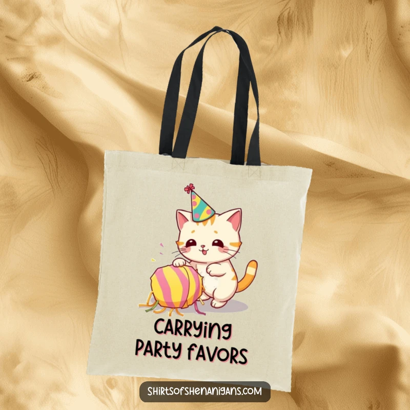 Funny tote bag with a cat in a party hat accidentally tipping a piñata, showcasing feline party antics.